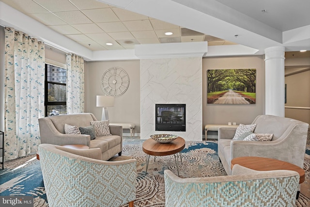 living room featuring a high end fireplace, decorative columns, a paneled ceiling, and recessed lighting