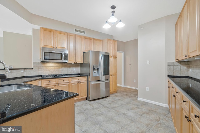 kitchen featuring a sink, visible vents, appliances with stainless steel finishes, dark stone countertops, and pendant lighting