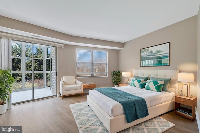 bedroom featuring light wood-style floors, access to exterior, and visible vents