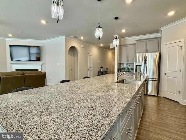 kitchen featuring stainless steel fridge, gray cabinets, dark hardwood / wood-style floors, a spacious island, and light stone countertops