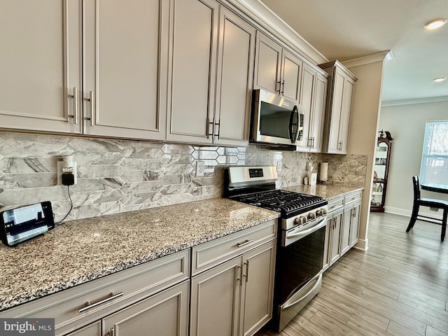 kitchen with stainless steel appliances, crown molding, tasteful backsplash, and light stone counters