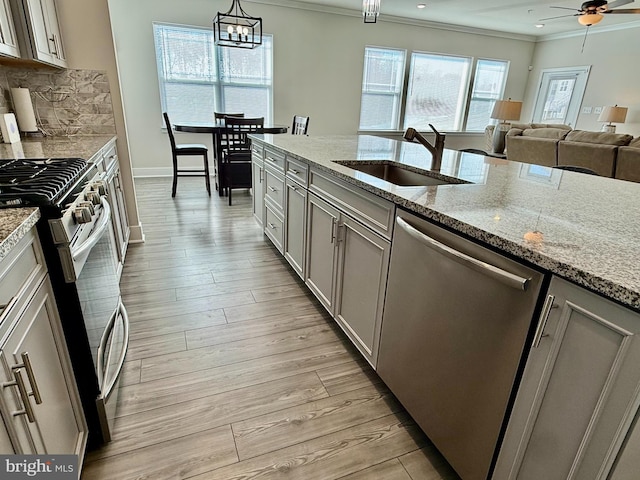 kitchen featuring pendant lighting, sink, crown molding, appliances with stainless steel finishes, and light hardwood / wood-style floors