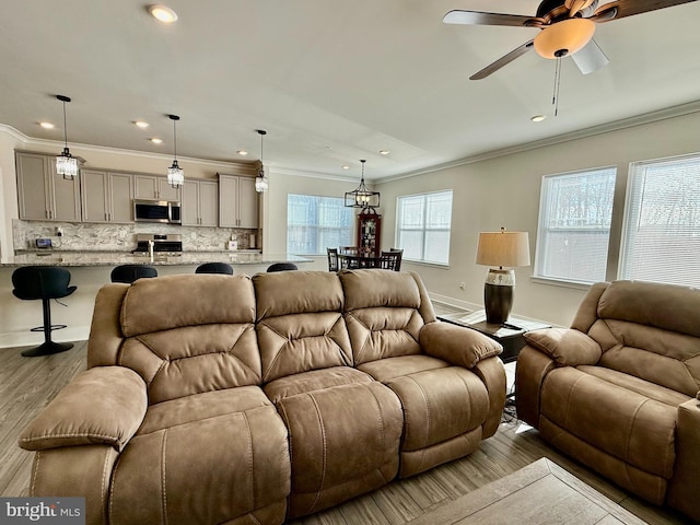 living room featuring light hardwood / wood-style flooring, ornamental molding, and ceiling fan