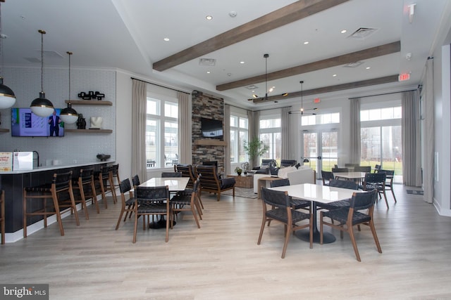 dining room with a fireplace, beamed ceiling, and light wood-type flooring