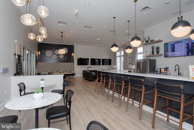 dining space with ornamental molding, sink, and light wood-type flooring