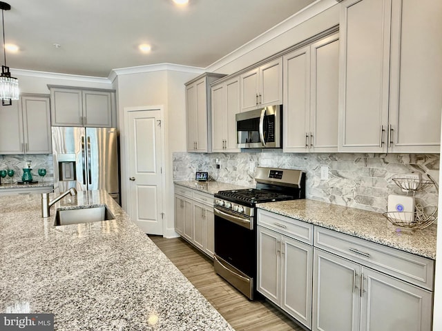 kitchen featuring appliances with stainless steel finishes, sink, backsplash, hanging light fixtures, and light stone countertops