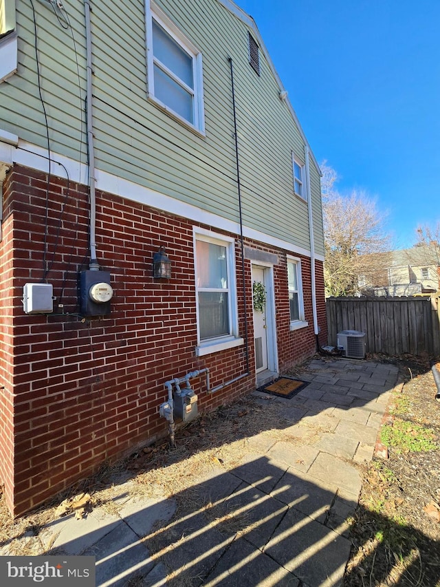 rear view of house with central AC unit and a patio