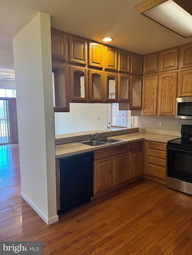 kitchen with black appliances, light countertops, a sink, and wood finished floors