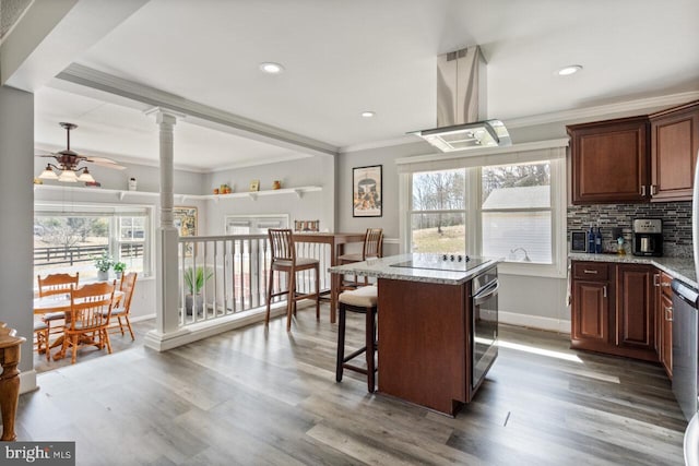 kitchen featuring decorative columns, ornamental molding, decorative backsplash, stainless steel appliances, and island range hood