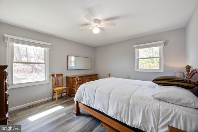 bedroom featuring visible vents, ceiling fan, baseboards, and wood finished floors