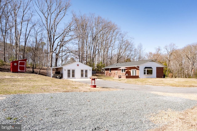 view of front facade with an outbuilding, french doors, driveway, and a front lawn