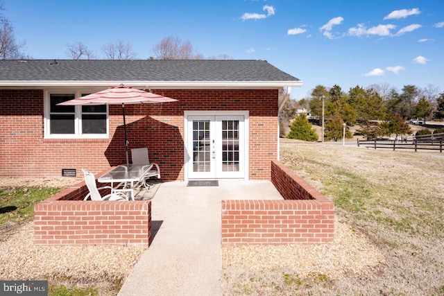 entrance to property with crawl space, fence, brick siding, and french doors