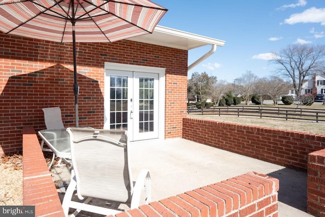 view of patio with french doors, outdoor dining area, and fence