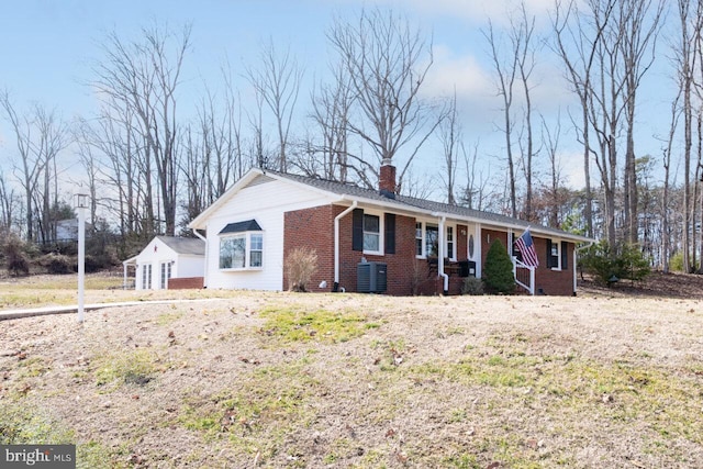 ranch-style house with brick siding, a chimney, and central AC