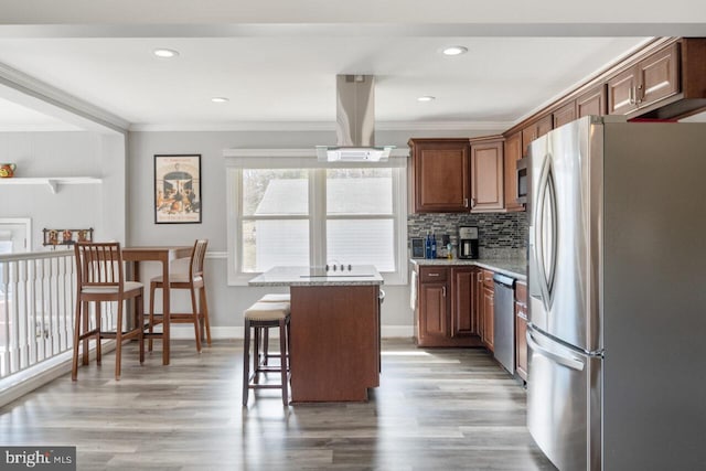 kitchen with light wood-type flooring, a kitchen bar, ornamental molding, backsplash, and stainless steel appliances