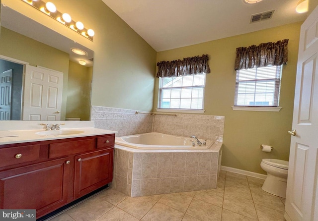 bathroom featuring lofted ceiling, a relaxing tiled tub, vanity, tile patterned floors, and toilet