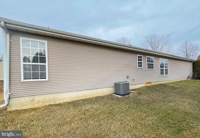 view of side of property featuring central AC and a lawn