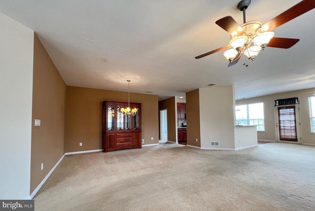 empty room with ceiling fan with notable chandelier and light colored carpet