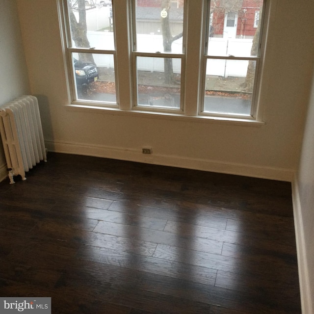 unfurnished room with dark wood-type flooring and radiator heating unit