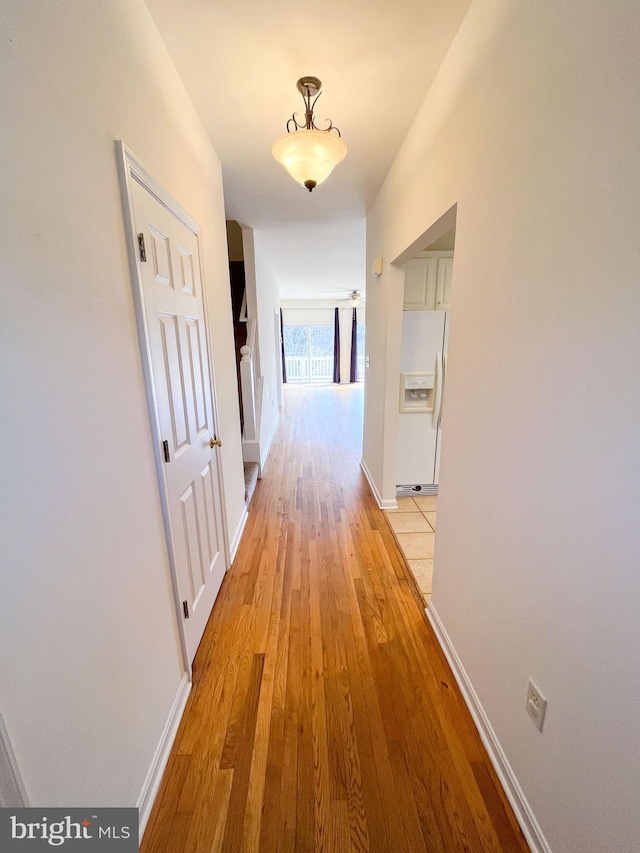 hallway featuring light wood-style flooring and baseboards