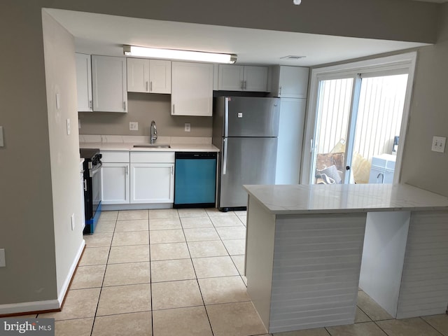 kitchen with sink, light tile patterned floors, kitchen peninsula, and appliances with stainless steel finishes