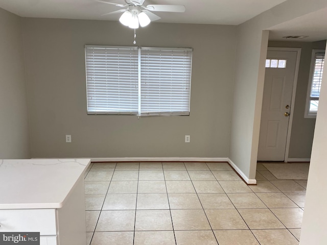 unfurnished dining area with light tile patterned flooring and ceiling fan