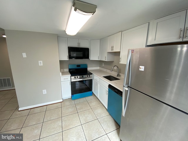 kitchen with light tile patterned floors, appliances with stainless steel finishes, sink, and white cabinets