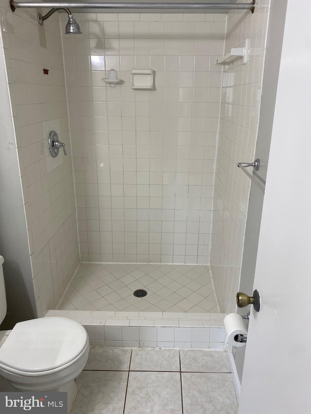 bathroom with tile patterned flooring, toilet, and tiled shower