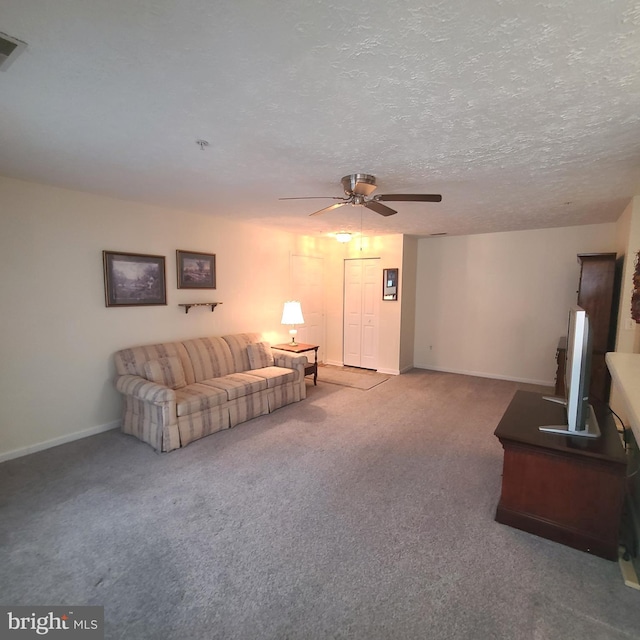 living room with ceiling fan, carpet floors, and a textured ceiling