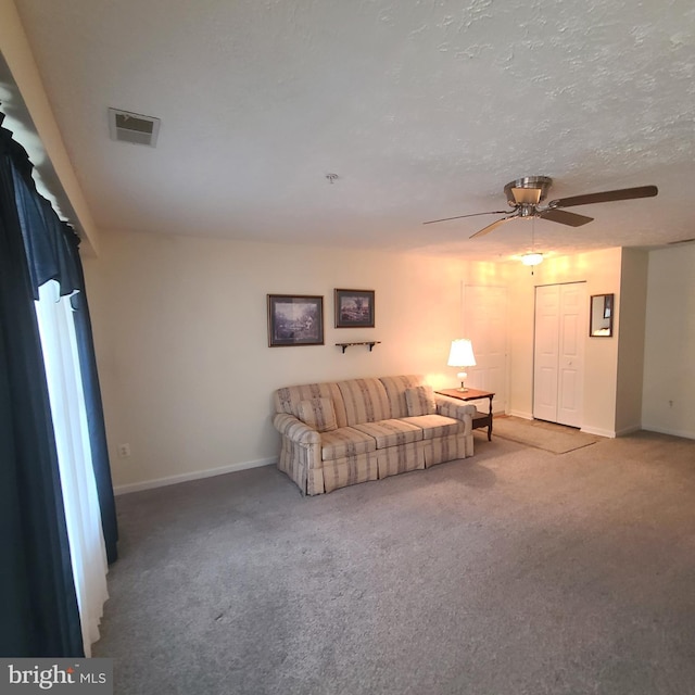 living room featuring ceiling fan, carpet flooring, and a textured ceiling