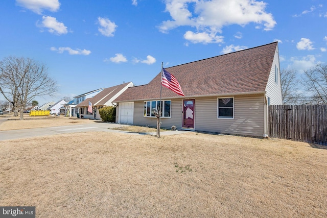 view of front of home featuring a front lawn, fence, roof with shingles, driveway, and an attached garage