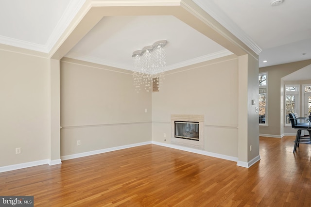 unfurnished living room with a notable chandelier, baseboards, wood finished floors, and a glass covered fireplace