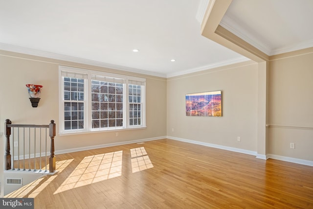 empty room featuring baseboards, crown molding, visible vents, and wood finished floors