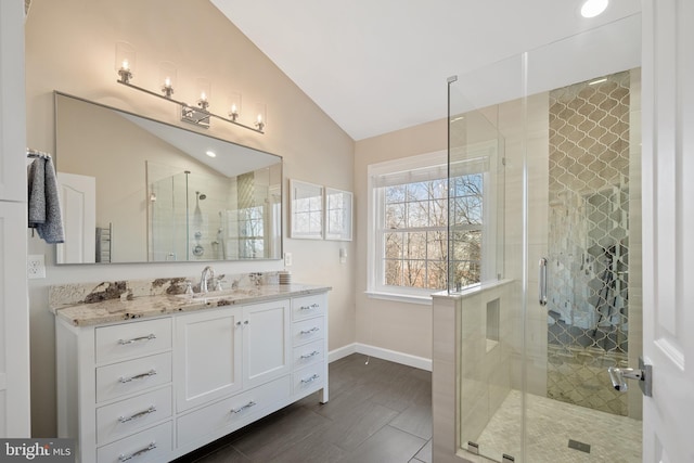 full bath with lofted ceiling, a stall shower, baseboards, and vanity