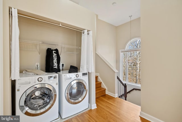 laundry area with laundry area, baseboards, washer and clothes dryer, and wood finished floors