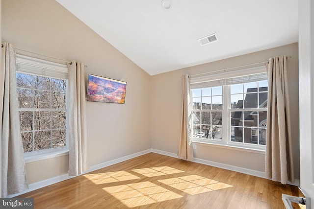 spare room with baseboards, visible vents, vaulted ceiling, and light wood finished floors