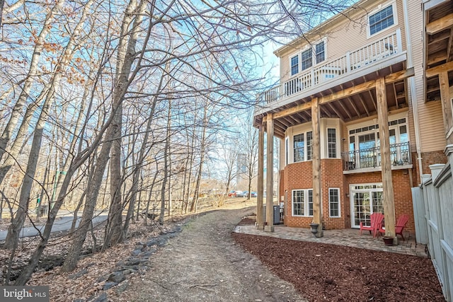 view of side of home featuring brick siding and a balcony