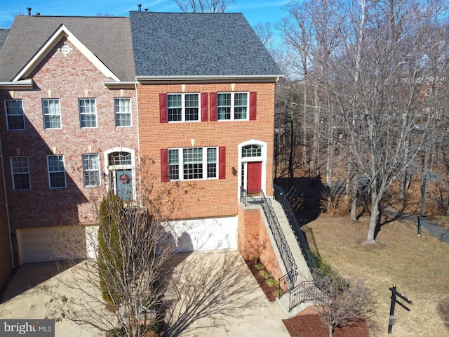 view of front of house with a garage, driveway, brick siding, and a shingled roof