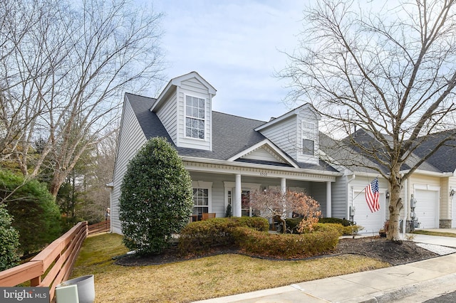 new england style home with a front lawn, a porch, and a garage