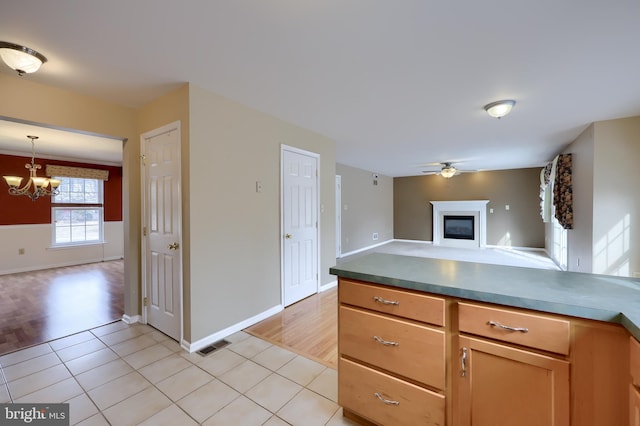 kitchen featuring light tile patterned floors, decorative light fixtures, and ceiling fan with notable chandelier