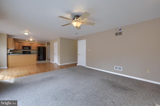 unfurnished living room with ceiling fan and light colored carpet