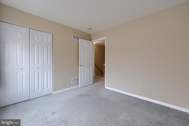 unfurnished bedroom featuring light carpet and a closet