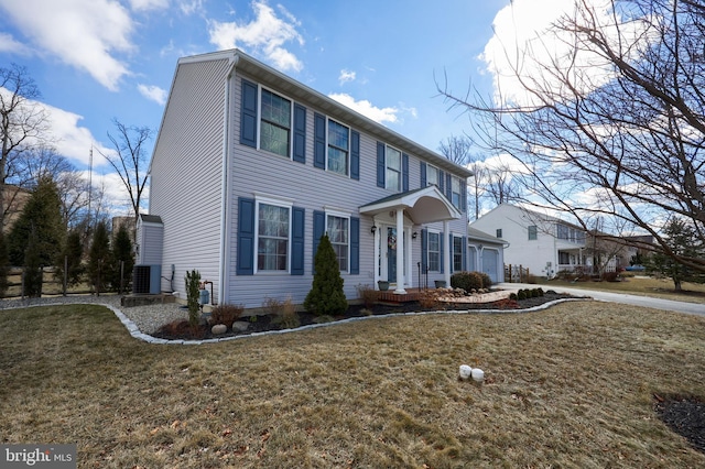 colonial home with a front yard, a garage, and central AC unit