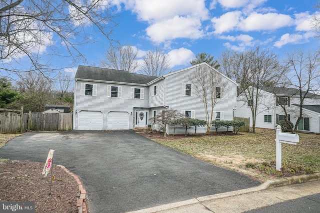 view of front of house with aphalt driveway, an attached garage, and fence