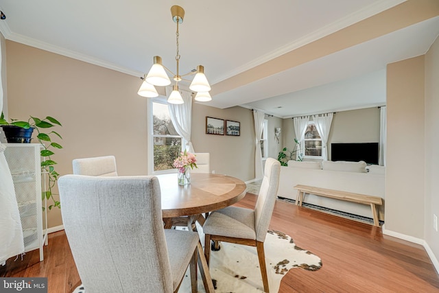 dining space featuring baseboards, a chandelier, wood finished floors, and crown molding