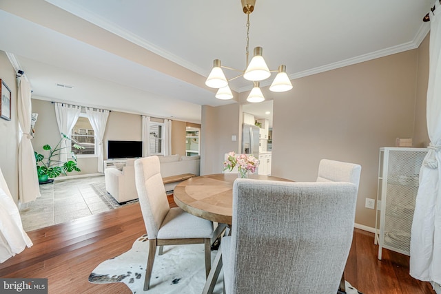 dining space with baseboards, crown molding, a chandelier, and wood finished floors