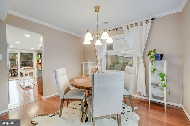 dining space with baseboards, light wood-type flooring, an inviting chandelier, and crown molding