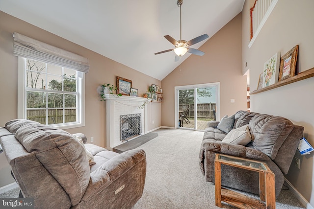 living room featuring baseboards, a fireplace with raised hearth, ceiling fan, carpet, and high vaulted ceiling