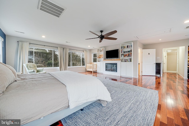 bedroom featuring recessed lighting, wood-type flooring, visible vents, and a glass covered fireplace