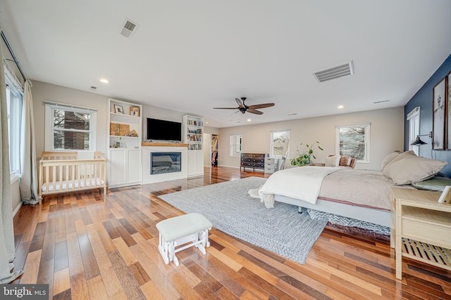 bedroom with a glass covered fireplace, visible vents, recessed lighting, and hardwood / wood-style flooring